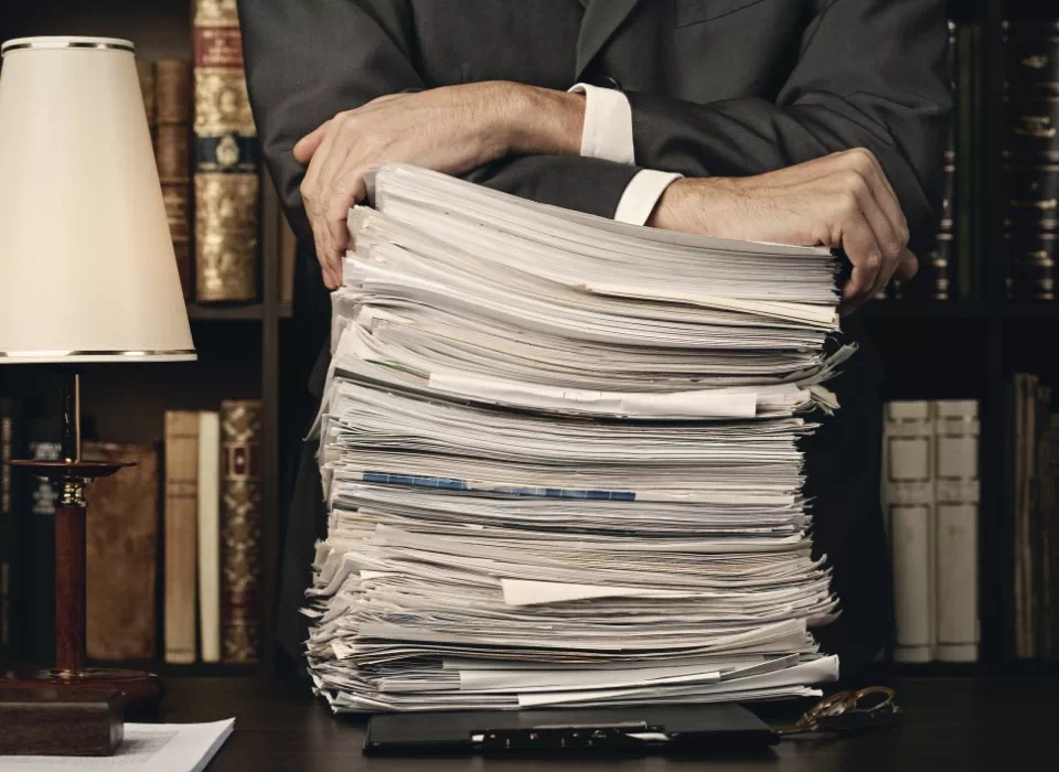 prawnik opierający&nbsp;się o&nbsp;stos dokumentów